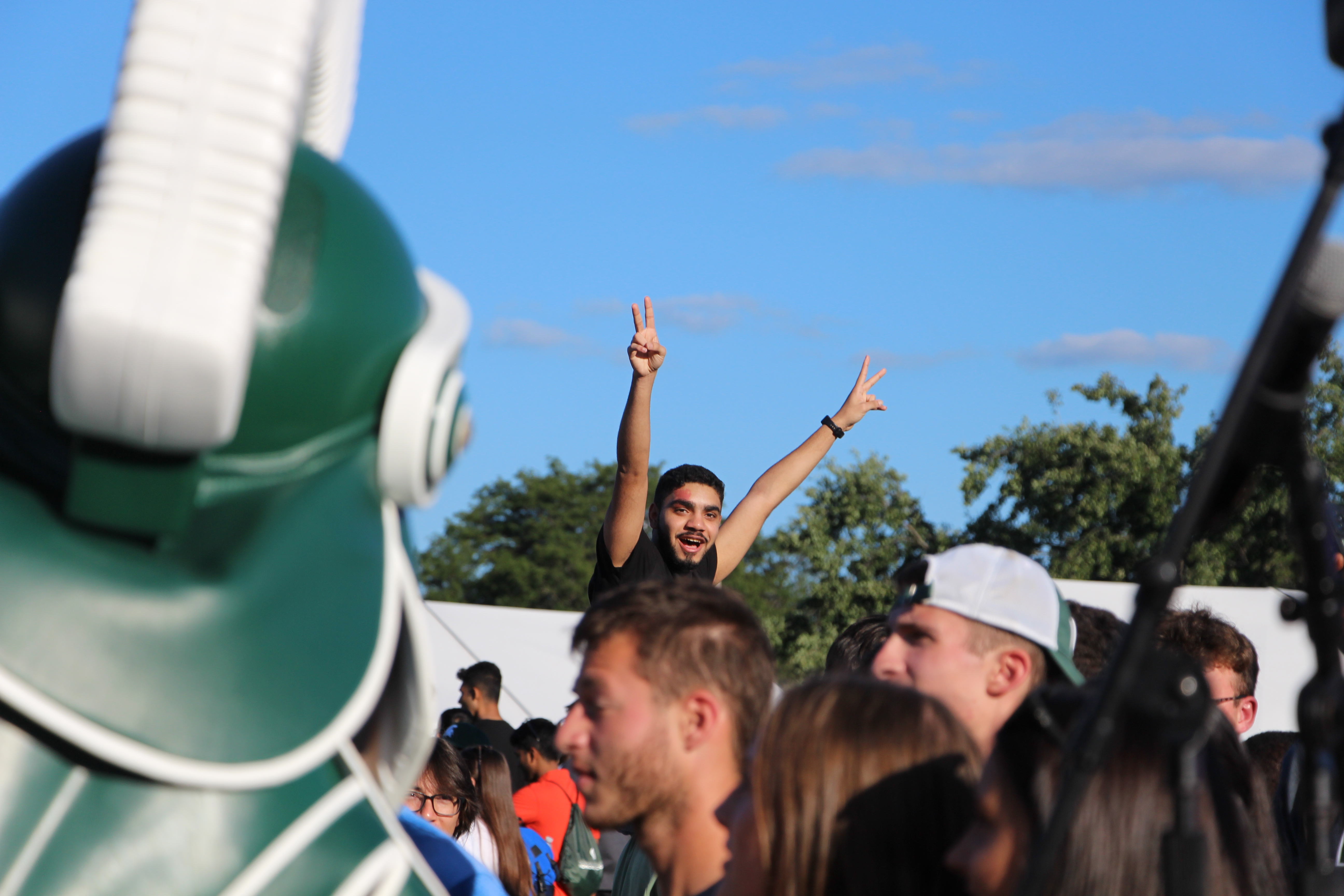 Student posing in a crowd with Sparty in foreground