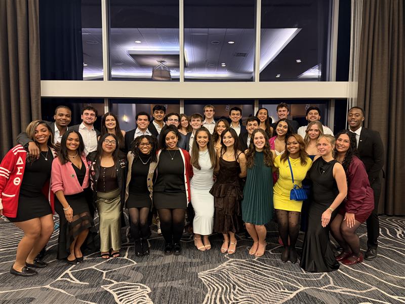 A host of FSL members standing in unity in front of a glass window