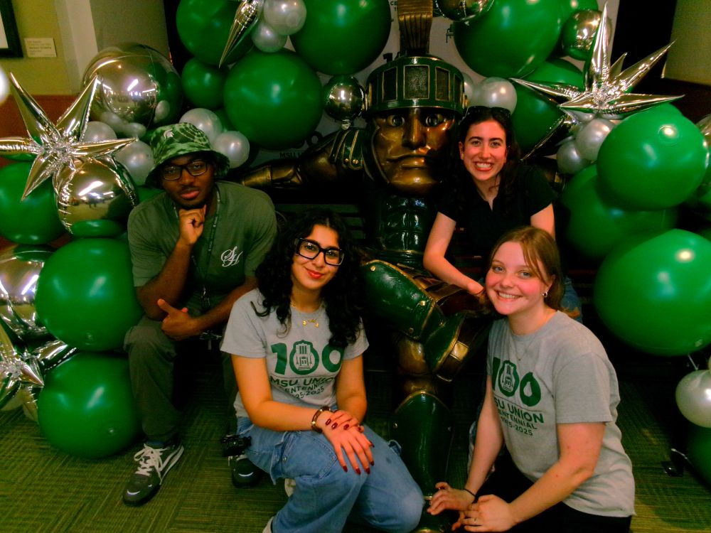 Students posing with Sparty statue, decorated in balloons