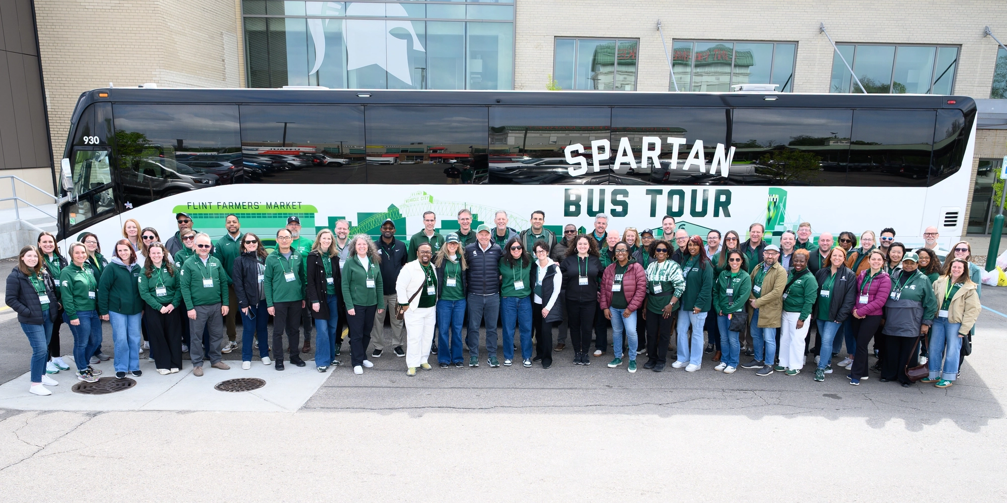 Group of administrators for Spartan Bus Tour standing in front of branded bus