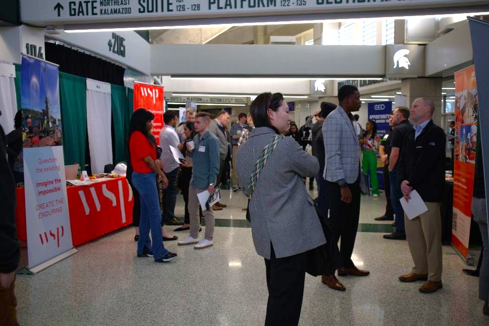 Career Fair attendees standing inbetween vendor booths, speaking to representatives