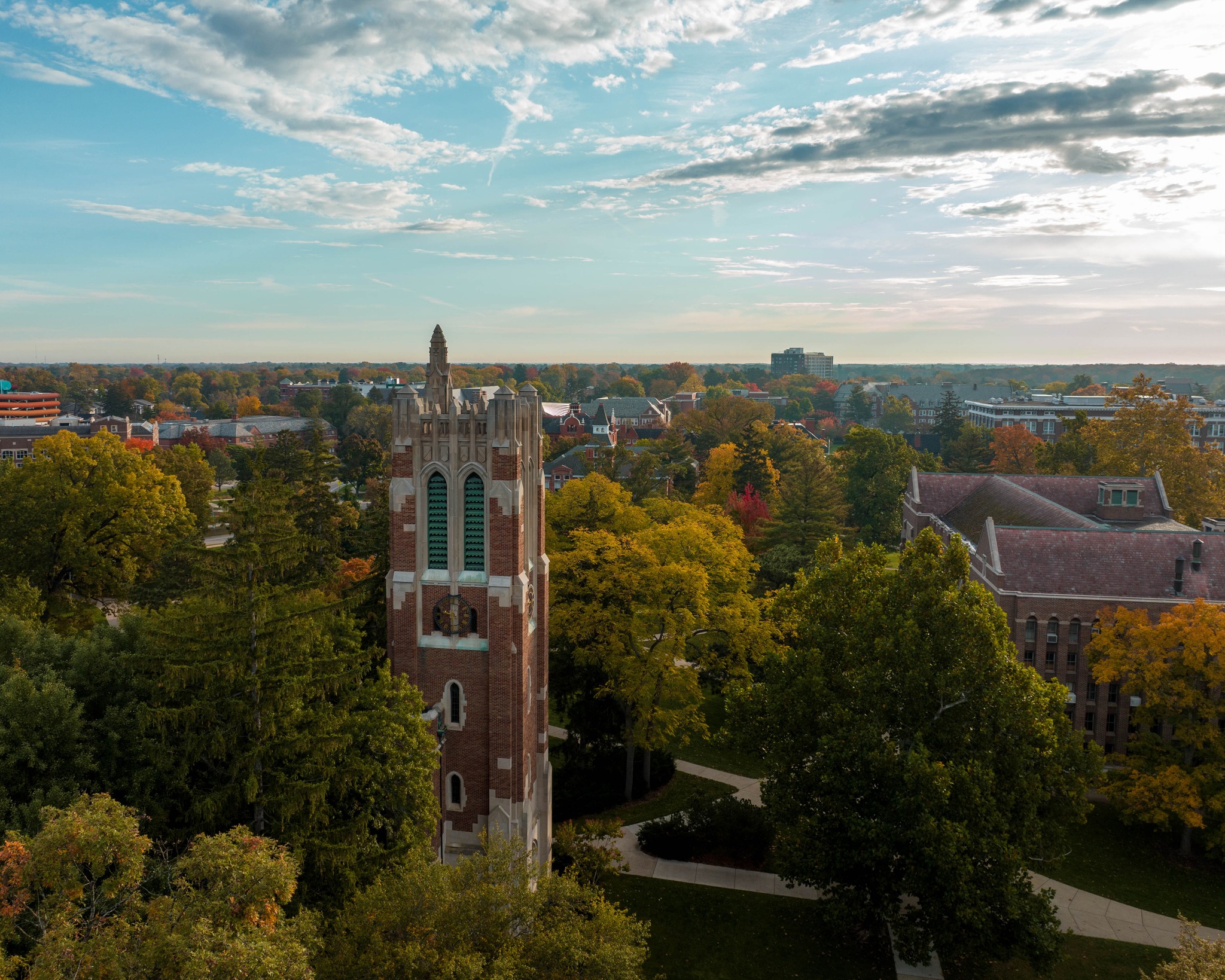 The Beaumont Tower from high in the sky in the foreground with a very green campus in the background