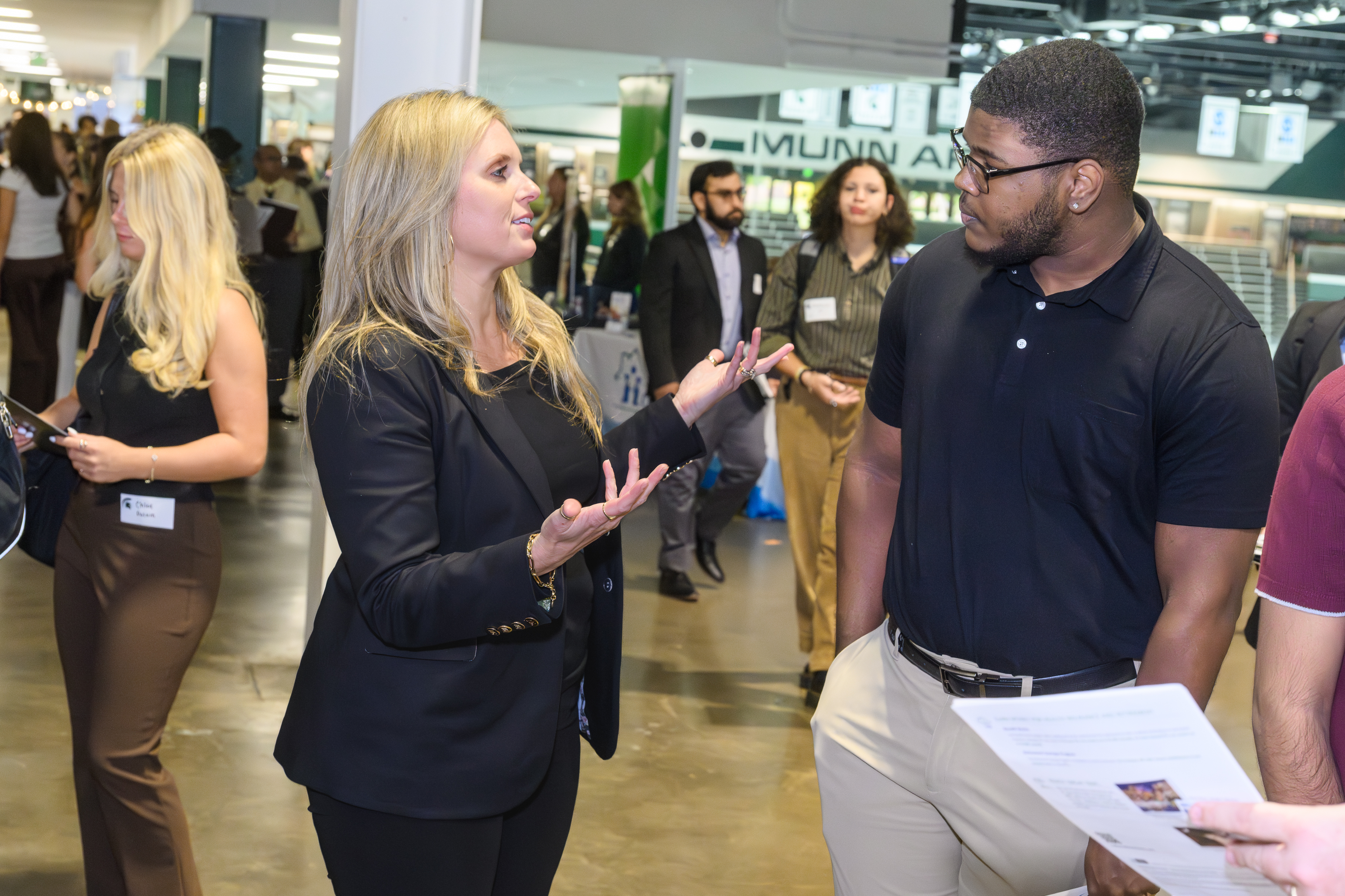 A student speaking to a company representative amongst others at a career fair