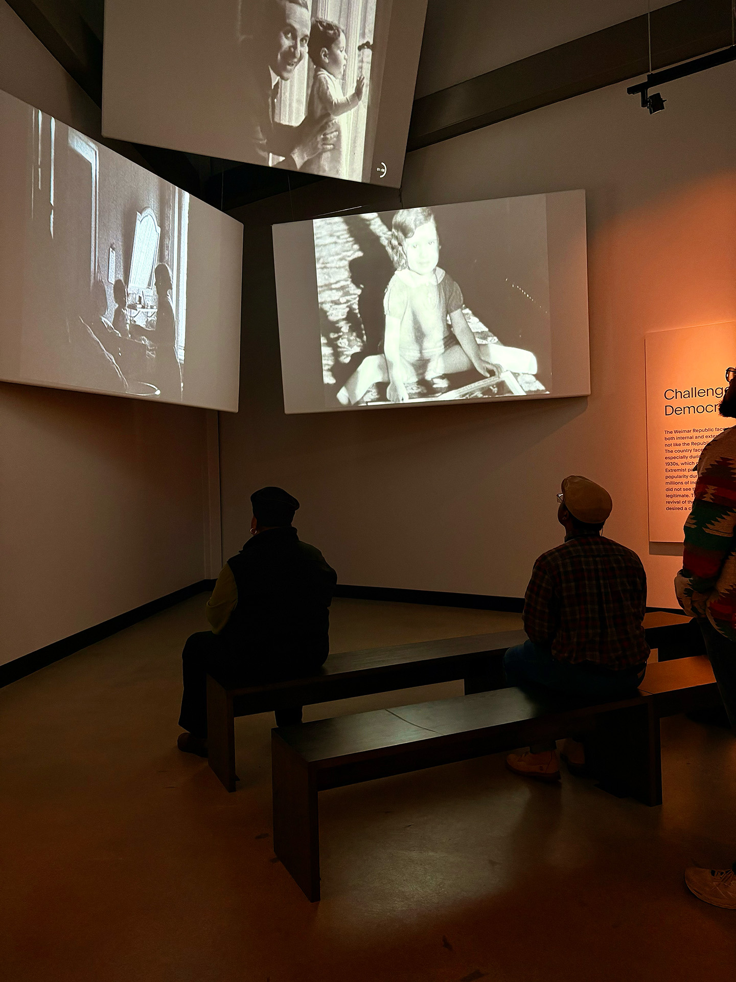 Seated visitors watch museum exhibit screen