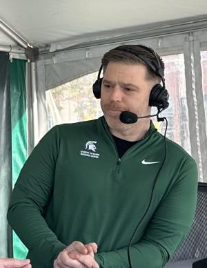 Patrick Forystek standing in MSU attire with a headset on his head