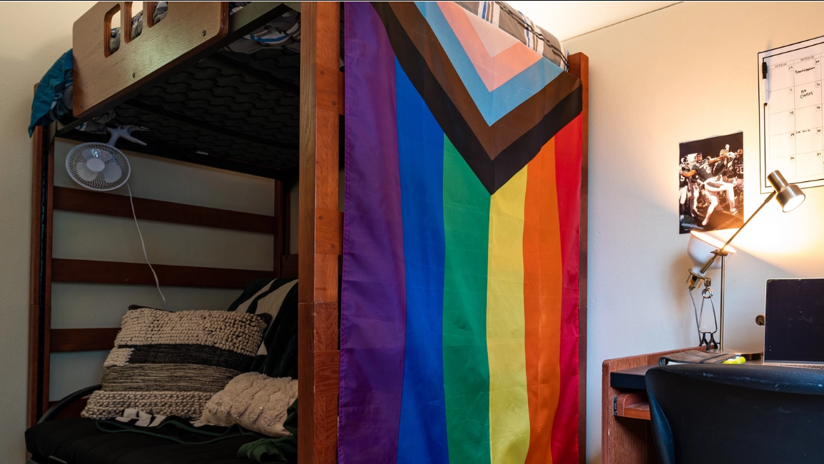 Decorated dorm room with desk, bed and displays shown prominently